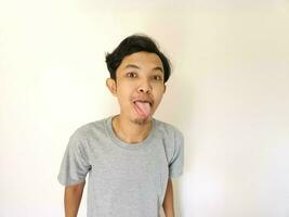 Funny tease and bully face of Asian man. sticking out tongue isolated on white photo