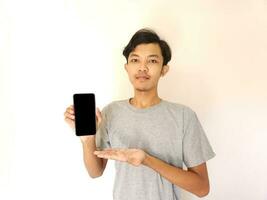 Asian young man showing smartphone with blank screen photo