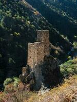 Hard-to-reach ancient battle towers on the rocks. Sunny afternoon in the Caucasus mountains. Medieval tower on green mountain forest background. Ingushetia region. photo