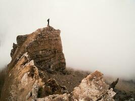 silueta de un solitario turista terminado un acantilado. agudo rocas místico foto