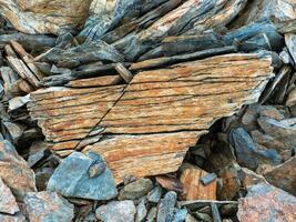 Layered mountain texture. Stone texture. Cross section of rocks. Geological layers. Colored layers of stones in section of the mount, different rock formations and soil layers. photo