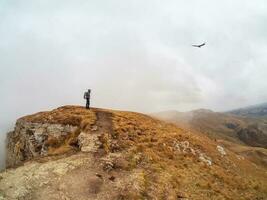 Tourist walks on mountain near abyss edge on high altitude under photo