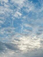 Jet military plane flies through clouds in a blue sky. Vertical view. photo