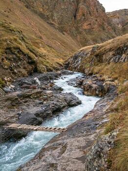 Tormentoso devanado montaña río. de madera improvisado puente terminado un mes foto