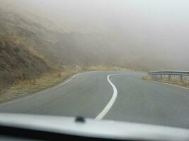 brumoso autopista. ver desde el conductor de el coche. vacío Mañana montaña autopista en un denso niebla. la carretera mediante un denso niebla. foto