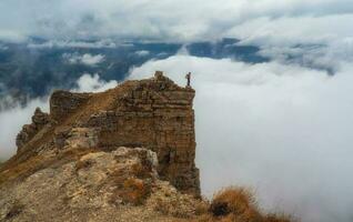 Tourist walks on mountain near abyss edge on high altitude under photo