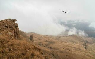 Low dense clouds over a mountain valley. Beautiful panoramic view to red mountain peaks over thick clouds. photo