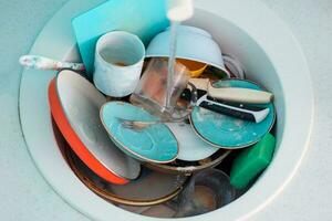 Sink with a pile of dirty dishes. Complete washing of crockery, tableware. Unsanitary conditions. photo