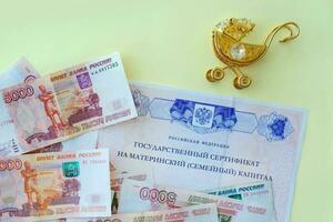 Small gold stroller and document with Russian text.  Russian money of five one thousand rubles. State benefits. photo