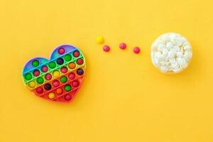 Use the popular pop it toy as a chocolate mold. Colorful candies lie in a silicone form in the form of a popit heart on a yellow background. DIY concept. Step-by-step photo instructions. Step 3.