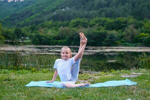 Beautiful happy girl with closed eyes practicing yoga in the lotus position near the lake in nature. photo