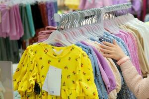 niño es manos son elegir ropa en el centro comercial. foto