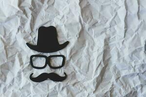 Happy Fathers Day sticker, black hat, glasses and mustache on crumpled paper background. Hipster objects. Father's Day is a holiday. Design Blank space for an inscription. photo