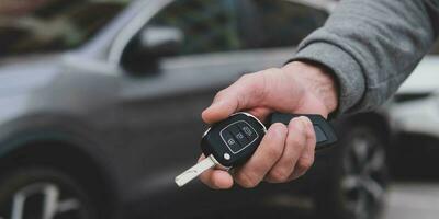 Man in front of the new car and holding keys. Salesman is carrying the car keys delivered to the customer at the showroom .  Rent, credit, insurance, car purchase. Copy space. Banner. photo