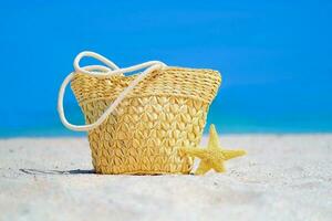 mujer es playa accesorios en el arena para un verano vacaciones concepto. Paja bolsa, estrella de mar. viaje antecedentes. foto