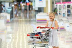 The child has filled a basket of books. Little girl in the book store. Sale. Child in the library with a trolly of books. photo