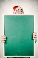 Man holding a blackboard wearing Santa hat photo