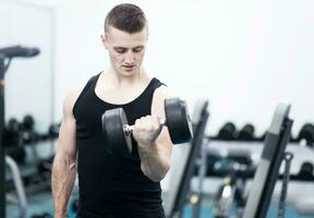 Athletic man with a dumbells in gym photo