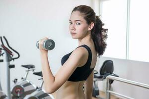 young fit woman lifting dumbbells photo