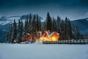 Emerald Lake with wooden lodge glowing in snowy pine forest on winter at Yoho national park photo