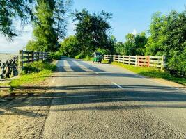 A road with a fence and a green vehicle photo