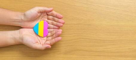 Pansexual Pride Day and LGBT pride month concept. hand holding pink, yellow and blue heart shape for Lesbian, Gay, Bisexual, Transgender, Queer and Pansexual community photo