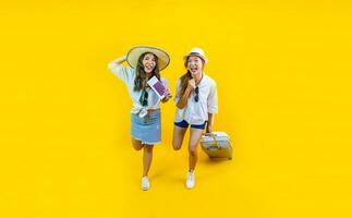 Two Pretty asian women passengers in trendy fashion is exciting to board while carrying her luggage bag in happiness for friendly trip and summer travel vacation isolated on yellow background photo