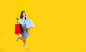 Pretty Asian woman in trendy summer fashion is smiling and holding shopping bag in happiness for discount sale isolated on yellow background for advertising and promotion event concept photo