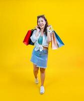 bonito asiático mujer en de moda verano Moda es sonriente y participación compras bolso en felicidad para descuento rebaja aislado en amarillo antecedentes para publicidad y promoción evento concepto foto