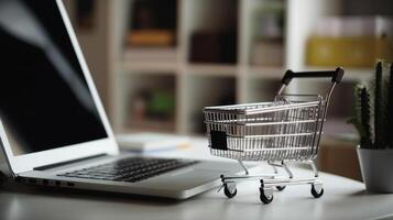 Shopping cart and laptop on the table. Online shopping concept. photo