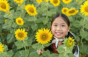 contento linda asiático niña sonrisa con girasol, foto