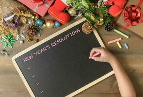 Kid writing New year resolution on black board photo