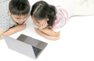 children lying down and watching cartoon on laptop photo