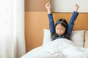 Asian cute girl wakes up and stretching on bed in morning photo