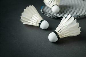 Shuttlecocks and badminton racket on black background. photo