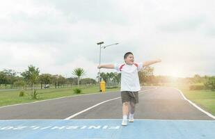 Happy asian fat boy running to the finished line. photo