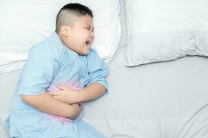 boy suffering from stomachache on bed photo