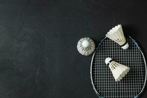 Shuttlecocks and badminton racket on black background photo