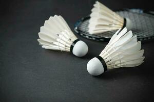 Shuttlecocks and badminton racket on black background. photo