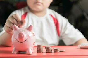 hand boy put coin to piggy bank, saving money photo
