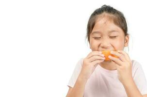 pequeño linda asiático niña disfrutar comiendo rebanado naranja foto