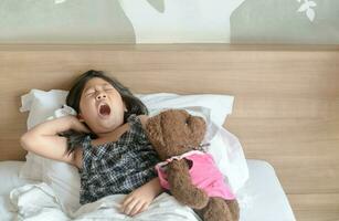 asiático niña despierta arriba y extensión en cama foto