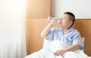 Obese fat boy drinking water on bed in morning photo