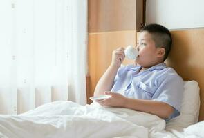 obese fat boy drinking hot milk on bed photo