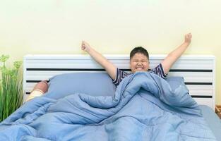 Fat boy stretching in bed after waking up, photo