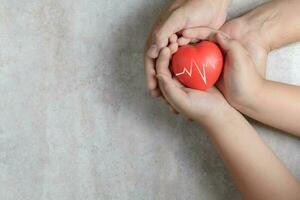 Father and child hands holding red heart on marble photo