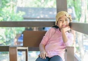 linda asiático niña sonrisa y sentado en antiguo silla, foto