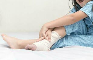 Little girl touching ankle with elastic bandage photo