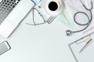 doctor desk table with stethoscope, coffee, Medical gown and notebook photo