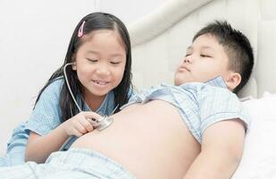 Cute girl check big stomach by stethoscope her brother photo